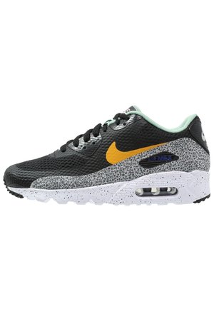 Baskets Nike Air Max noires et grises avec logo jaune, semelle intermédiaire tachetée, lacets noirs et doublure intérieure vert clair.