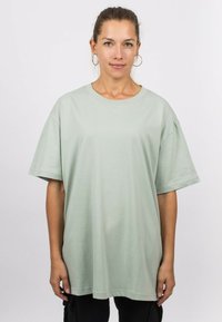 Mint green oversized t-shirt made of soft cotton, featuring short sleeves and a round neckline, with a relaxed fit and minimal seams.