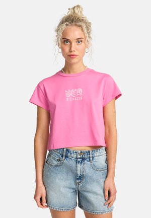 T-shirt court rose en coton, avec manches courtes et col rond. Texte graphique blanc et design sur le devant.