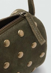 Borsa in camoscio verde oliva con chiusura a zip, caratterizzata da grandi borchie in bronzo distribuite uniformemente sulla superficie. Finitura testurizzata e manico corto.
