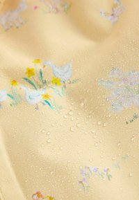 Kollane kangas veepiisakestega, millel on pehmetes pastelltoonides hane-, lille- ja liblikamotiivid. Sile tekstuur.