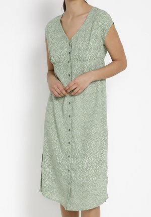 Robe à imprimé floral vert avec de courtes manches courtes, décolleté en V et fermeture à boutons sur le devant ; elle présente une coupe décontractée et des fentes sur les côtés.