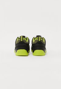 Sorte og limegrønne sneakers med en struktureret overflade, der har en robust sål, polstret krave og en løkke bagpå for nem påtagning.