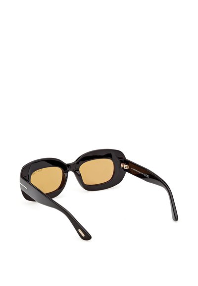Schwarze rechteckige Sonnenbrille mit dicken Rahmen und bernsteinfarben getönten Gläsern, die auf einer weißen Oberfläche liegt.