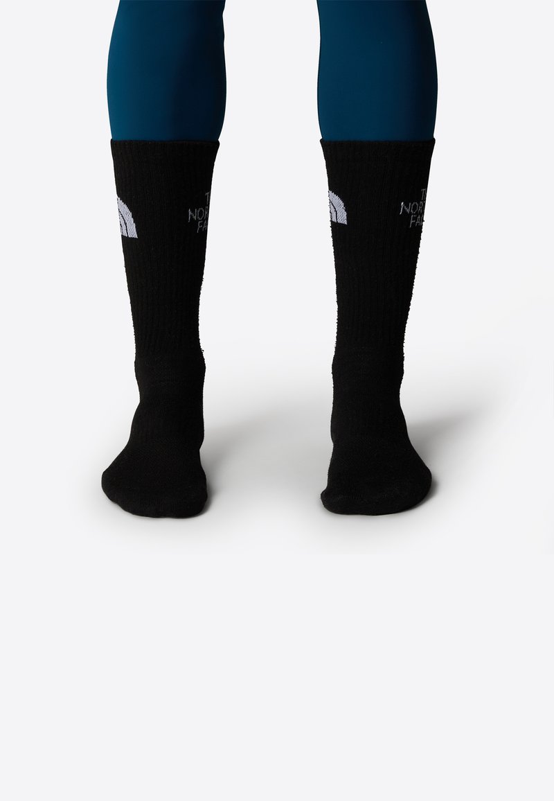 Calcetines negros de punto con textura acanalada, que presentan un diseño de logotipo blanco en el puño. Los calcetines son de longitud hasta el tobillo, con un ajuste ceñido.