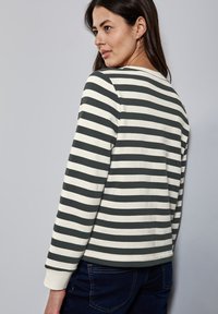 Sudadera de rayas en verde oscuro y crema con mangas largas, escote redondo y puños acanalados. Tejido suave, corte relajado y diseño sencillo.