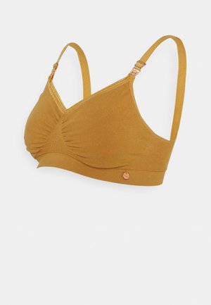 Mustard yellow wireless bra featuring soft fabric, a ruched design on the front, adjustable straps, and a small logo accent.