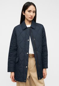 Μπουφάν σε σκούρο μπλε χρώμα με καπιτονέ ύφασμα, γιακά όρθιο, μπροστινό φερμουάρ και κουμπιά επάνω. Διαθέτει πλαϊνές τσέπες και υφή στην επιφάνεια.