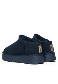 Granatowe botki za kostkę wykonane z zamszu, z miękkim, futrzanym wnętrzem, z grubą podeszwą i metką z logo na pięcie.