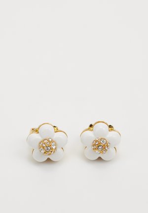 Pendientes en forma de flor, en color dorado y blanco, con seis pétalos y un racimo de pequeños cristales transparentes en el centro sobre un fondo blanco.