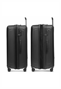 Dos maletas duras negras con cuatro ruedas y asas telescópicas, una completamente cerrada con cremallera y la otra parcialmente abierta.