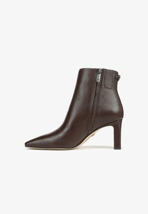 Bottine en cuir marron avec un bout pointu, un talon fin et une fermeture éclair sur le côté, présentant une texture lisse et un design minimaliste.