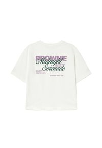 Camiseta blanca de manga corta con texto en morado y verde oscuro: "BROWNIE Serenata de Medianoche" y frases adicionales más pequeñas en la parte de atrás.