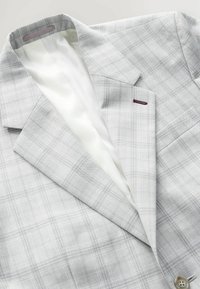 Blazer de cuadros en gris claro con solapas estructuradas, cierre de un solo botón y forro blanco. Presenta un pequeño acento burdeos en el bolsillo.