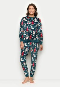 Fleecová pyžamová souprava v tmavě tyrkysové barvě se vzorem psů a králíků v slavnostních oblecích. Obsahuje dlouhý rukáv a kalhoty ve stylu jogger.