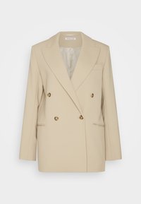 Beige Doppelreiher-Blazer mit breiten Revers, vier Knöpfen vorne, zwei Fronttaschen und einer Brusttasche, offen getragen.