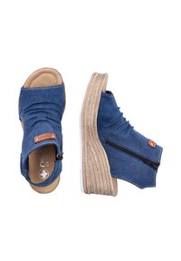 Sandales compensées en denim bleu avec fermetures éclair latérales et semelles plateformes texturées couleur liège clair, vues de dessus et de côté sur fond blanc.