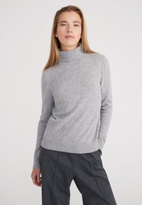 Maglione grigio chiaro a collo alto in un morbido tricot, con maniche lunghe e vestibilità rilassata. L'orlo e i polsini a coste aggiungono una leggera texture.