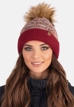 Knit beanie with a maroon band and beige patterned upper. Features a large faux fur pom-pom on top and a small branded tag on the side.