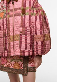 Πεταλωτή ροζ ζακέτα με φτιαξίματα καρό σε μπορντό και πράσινο. Διαθέτει δύο μπροστινές τσέπες και γιακά από κοτλέ. Ορατή συντονισμένη φούστα με σχέδιο.