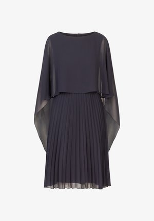 Vestido plisado en azul marino oscuro, con un fluido superpuesto tipo capa y mangas transparentes. Tejido suave con una textura sutil. Cierre en la parte posterior con abertura en forma de llave.