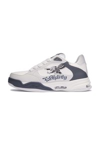 Zapatilla blanca con acentos grises, que presenta un upper texturizado, suela acolchada y un gráfico de águila junto con la marca "Ed Hardy".