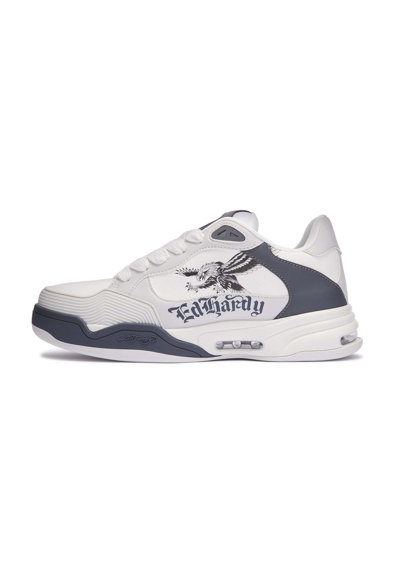 Zapatilla blanca con acentos grises, que presenta un upper texturizado, suela acolchada y un gráfico de águila junto con la marca "Ed Hardy".