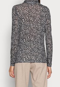 Långärmad topp i genomskinligt tyg, med ett virvlande mönster i svart, grått och kräm, med hög krage och rak nederdel.