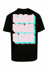 Sort t-shirt med fed, tredimensional tekst i pink, blå og grøn, der står "Good Vibes Only" på ryggen. Korte ærmer.