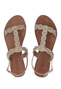 Tan vlakke sandalen met een beaded T-strap ontwerp, voorzien van doorzichtige en gouden accenten op een zachte brown zool. Te verstellen met een zijschoen gesp.
