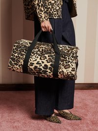 Bolsa de deporte de estampado de leopardo con correas y cremallera negras. Combinada con pantalones vaqueros y zapatos de punta sin cordones con un estampado a juego.