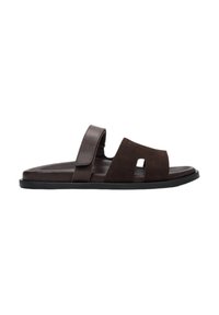 Brown suede slide sandal featuring a split design, adjustable strap, and a textured insole, complemented by a black rubber sole.