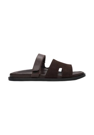 Brown suede slide sandal featuring a split design, adjustable strap, and a textured insole, complemented by a black rubber sole.