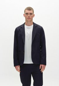 Navy blue, lightweight blazer with a relaxed fit, two front pockets, and notch lapels, paired with a white crew-neck t-shirt.