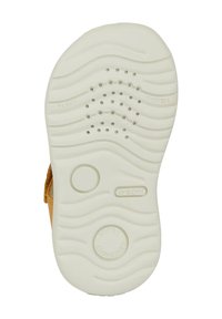 Suela de zapatilla de goma blanca, con un patrón ondulado y agujeros de ventilación. Etiquetas en relieve de "GEOX", "FLEXY" y "SUAVEMENTE ACOGEDOR".