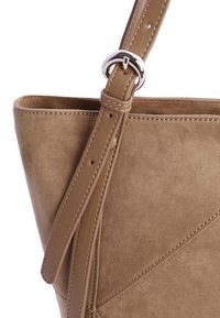 Bolso de ante marrón con un acabado texturizado, que presenta una correa de cuero suave y herrajes de anillo plateados. Diseño de paneles geométricos.