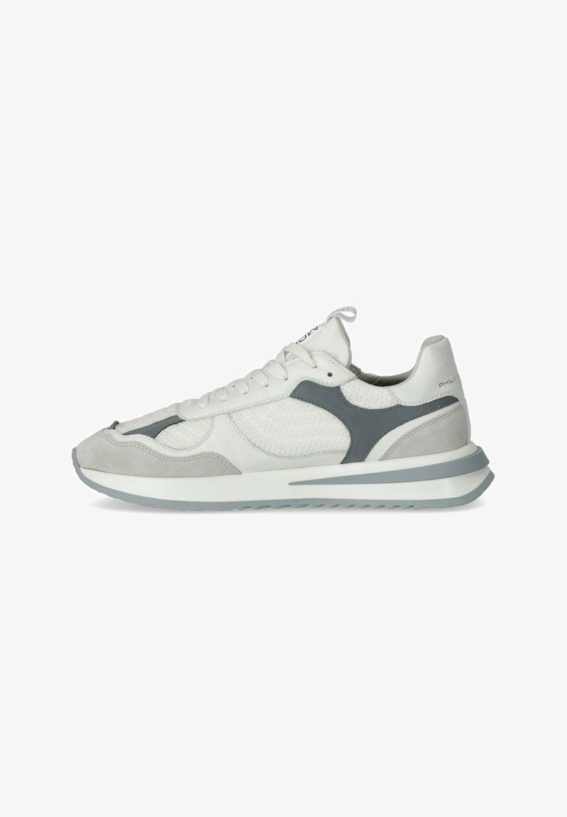 White athletic shoes with a textured mesh upper, grey suede accents, and a contrasting rubber sole. Features lace-up design and branding.