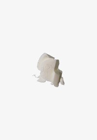 White, textured slab of solid cosmetic product with a smooth surface and curved edges, showing a slight sheen and irregular breaks.