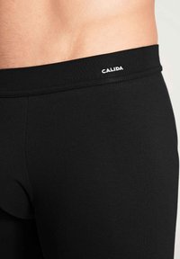 Zwarte katoenen stretch ondergoed met een zachte tailleband waarop het logo "CALIDA" in het wit is gedrukt, aansluitend ontwerp met een gladde textuur.