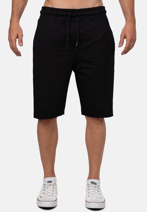 Schwarze Baumwoll-Shorts mit einem elastischen Bund und Kordelzug. Verfügt über seitliche Taschen und eine lockere Passform, die knapp oberhalb des Knies endet.