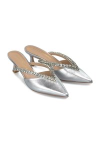 Zilveren metallic slingback hakken met puntige neus, versierd met een rij heldere edelstenen langs de V-vormige band. Lage kittenheels.