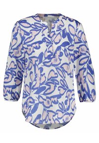 Blouse à manches longues blanche avec des motifs floraux bleus et roses, dotée d'un col en V, d'une coupe décontractée et d'un ourlet arrondi. Texture de tissu lisse.