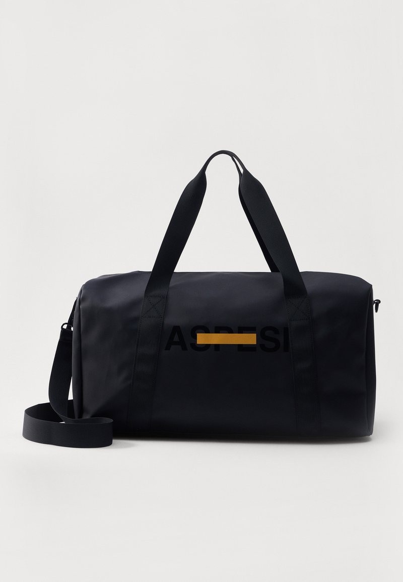 Black duffel bag made of durable material, featuring double handles, removable shoulder strap, and a yellow accent line with the word "ASPRE."