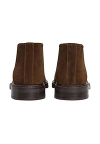 Hnědé semišové kotníkové boty s hladkou texturou, zúženým dřevěným podpatkem a viditelným stehem podél švů. Jednoduchý design.