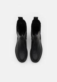 Czarne skórzane botki za kostkę z elastycznymi panelami bocznymi, okrągłym noskiem i przeszyciami. Prosty design, gładka faktura i styl zakładany na stopę.