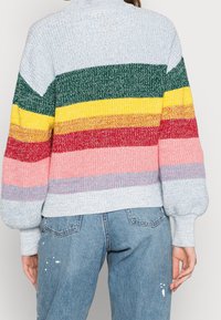 Pull encolure haute multicolore présentant des rayures bleu clair, vert, jaune, rouge, rose et gris. Il a des poignets côtelés.