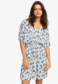 Bloemige jurk met V-hals, korte mouwen en elastische taille. Bevat blauwe, roze en groene bloemen op een lichte achtergrond. Lichtgewicht stof.