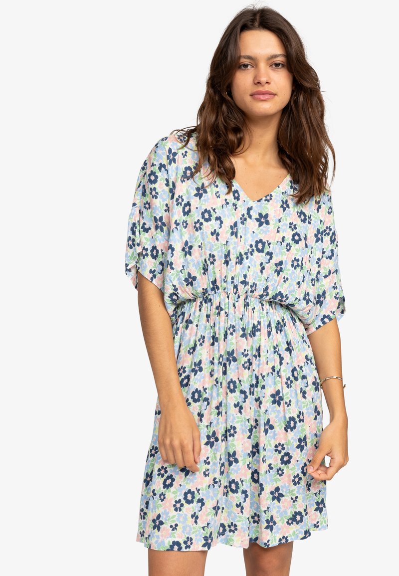 Bloemige jurk met V-hals, korte mouwen en elastische taille. Bevat blauwe, roze en groene bloemen op een lichte achtergrond. Lichtgewicht stof.