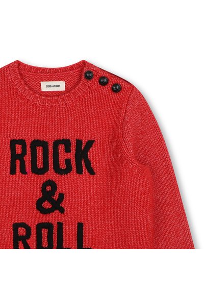 Κόκκινο πλεκτό πουλόβερ με μαύρο κείμενο "ROCK & ROLL", στρογγυλή λαιμόκοψη και τρία μαύρα κουμπιά στον αριστερό ώμο.