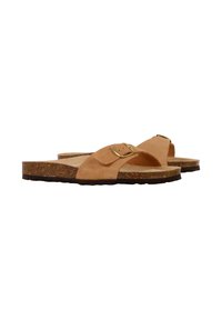 Tan suède slip-ons met een kurken voetbed en een enkele band met een gouden gesp, op een gestructureerde bruine rubberen zool.